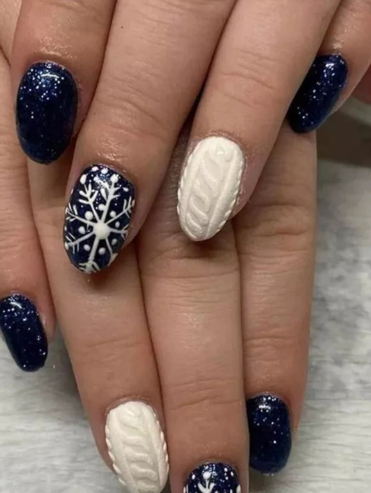 Blue and white winter manicure with snowflake and sweater-texture designs for cozy December Nails