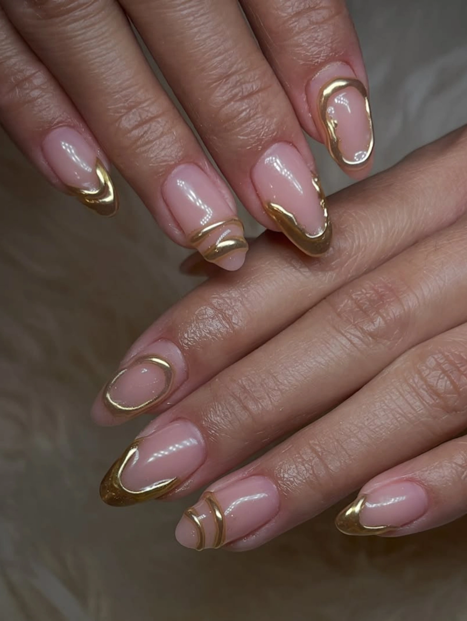 Uñas para Nochevieja con efecto cromo dorado y detalles de cristales decorativos.