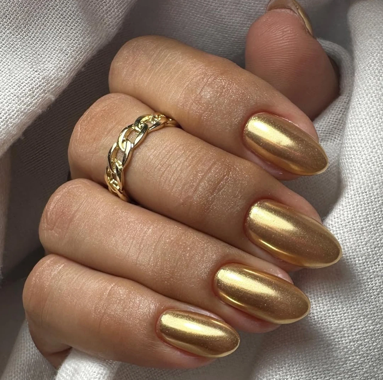 Uñas cromo dorado elegantes con acabado metálico brillante.