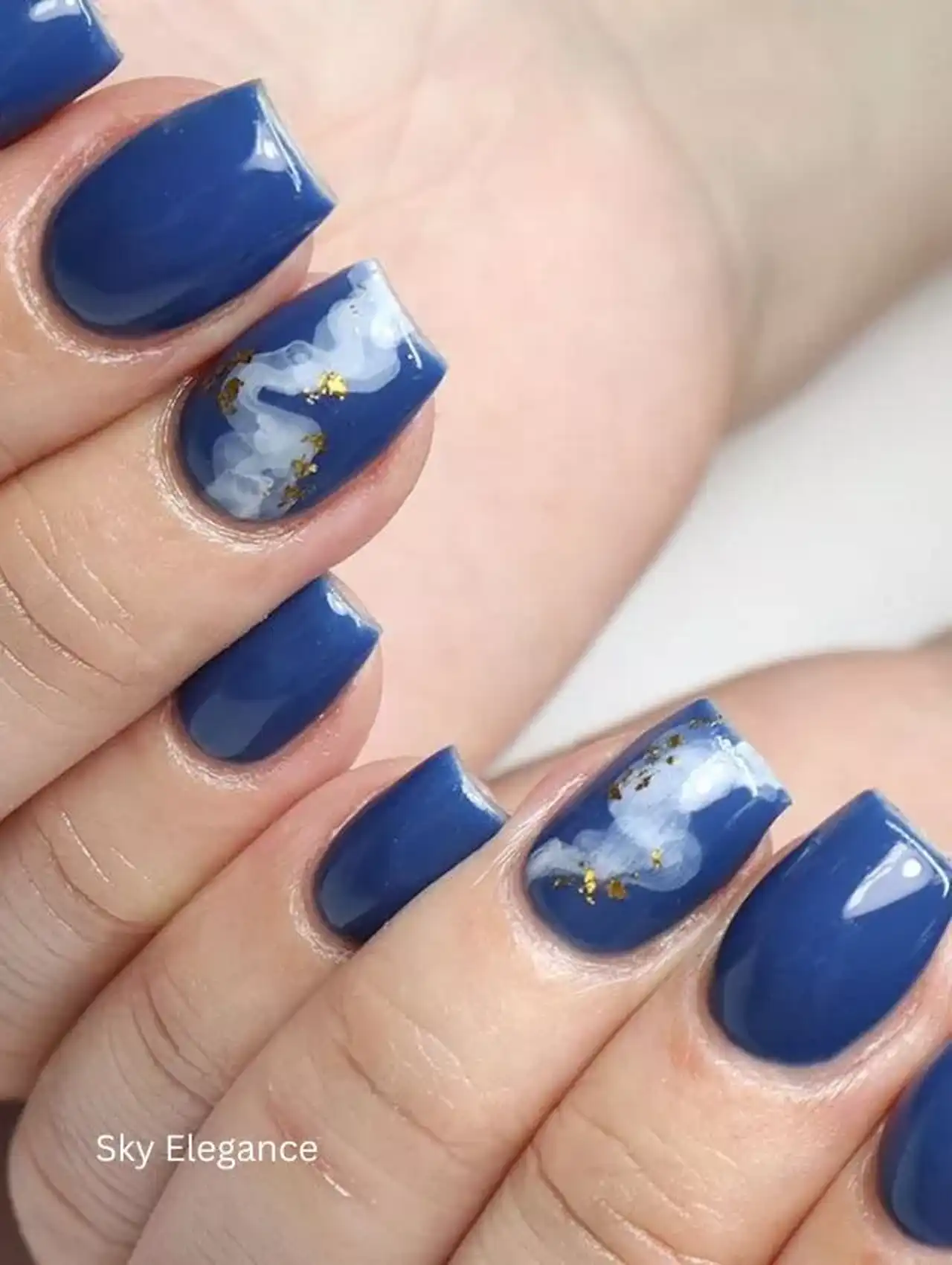 Uñas de invierno azules con detalles en blanco y dorado estilo cielo