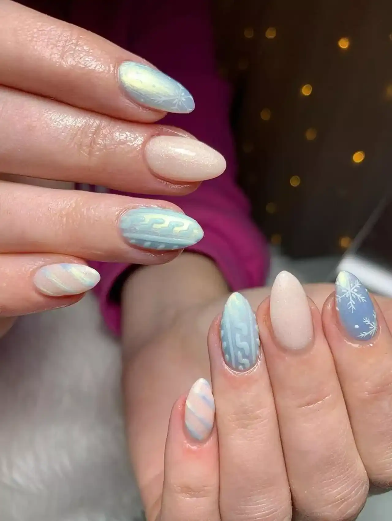 Uñas de invierno en tonos pastel con copos de nieve y efecto suéter