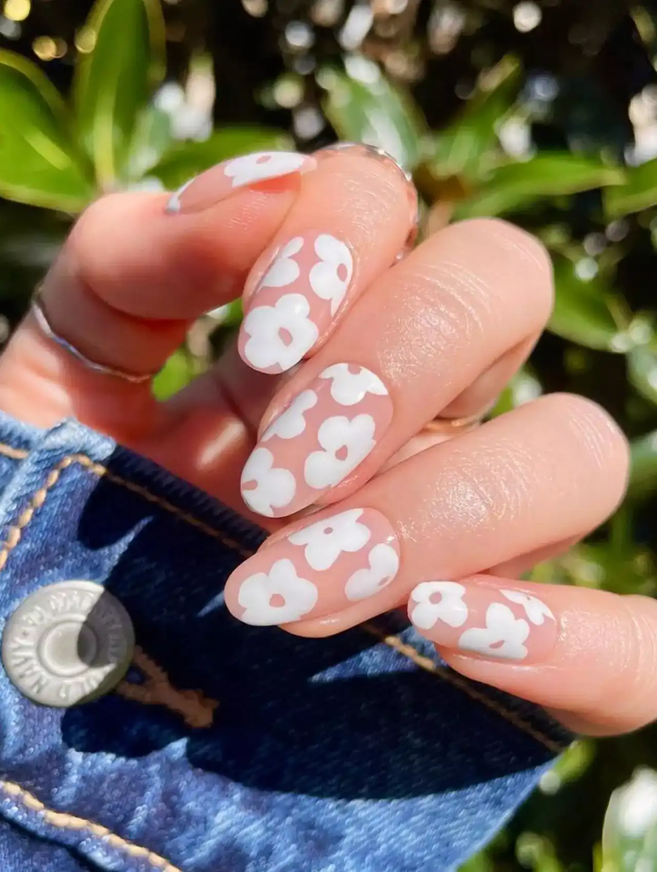 White nail polish with bold mod-style floral designs on clear base.