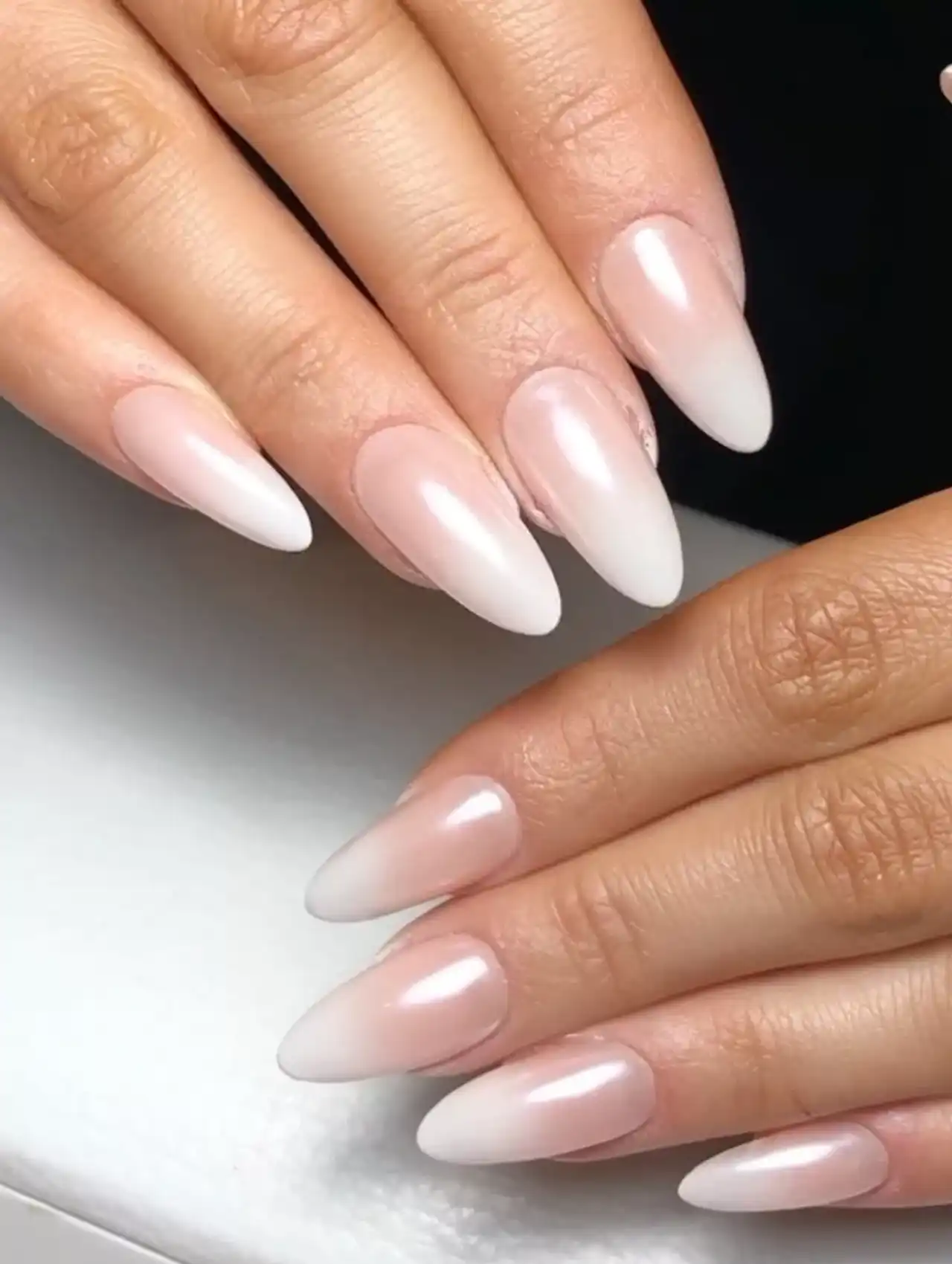 Ombré white nail polish with chrome finish on almond-shaped nails.