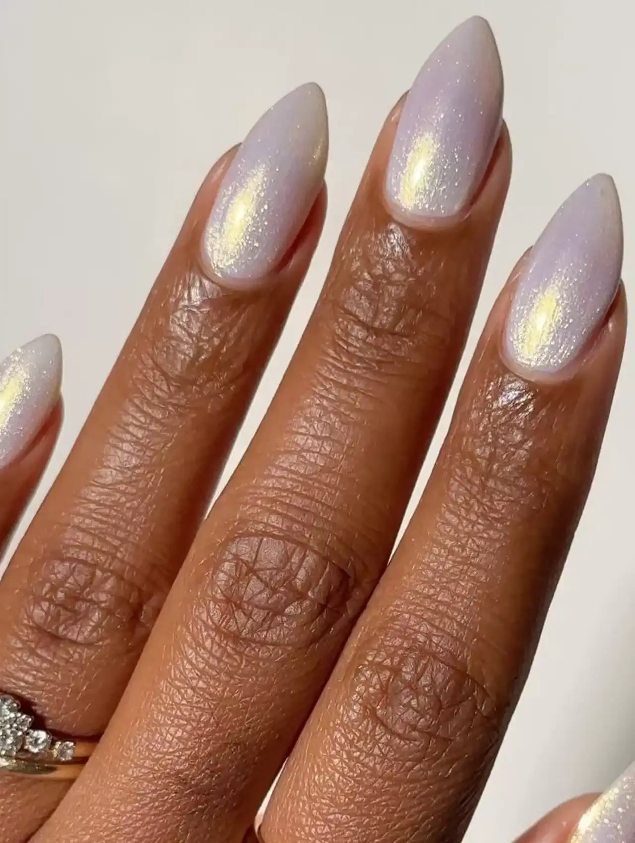 Almond-shaped nails with pearlescent white nail polish and subtle shimmer.
