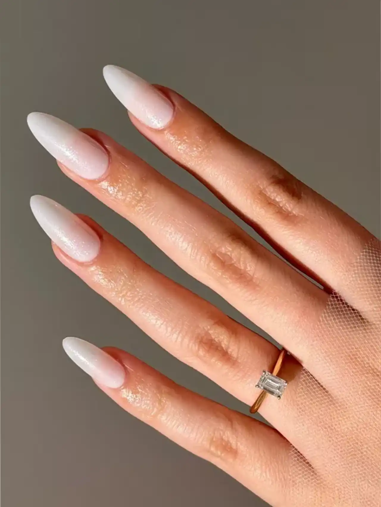 White nail polish with subtle shimmer on almond-shaped nails.
