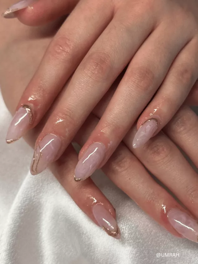 Sheer pink almond-shaped nails with delicate gold details.