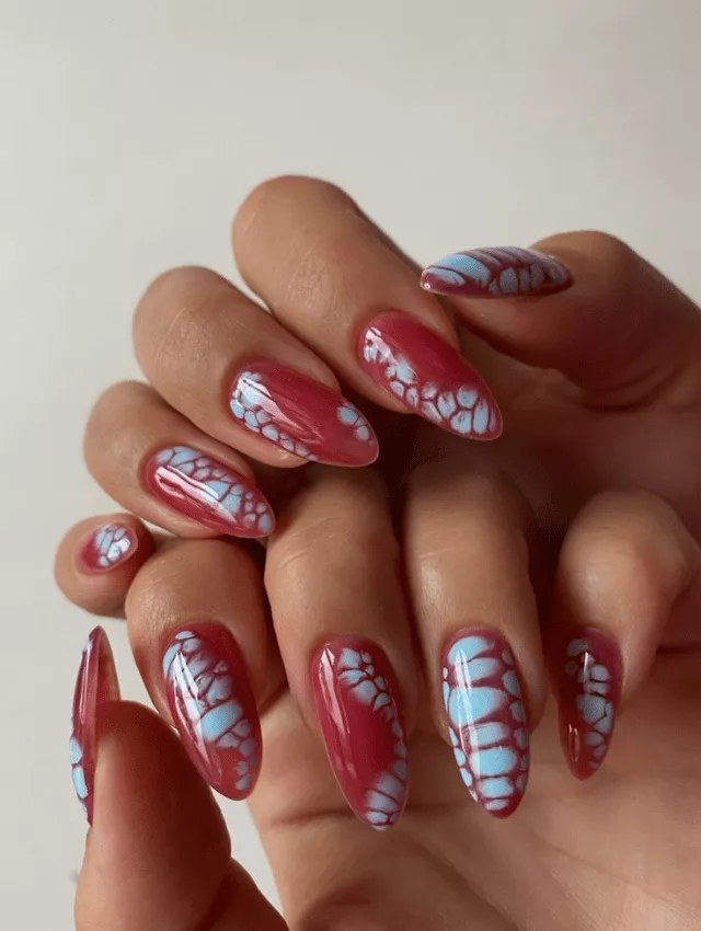 Bold red almond nails with blue blooming designs.