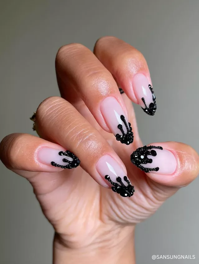 A bold black beaded drip nail design on a nude base, creating a striking 3D effect.