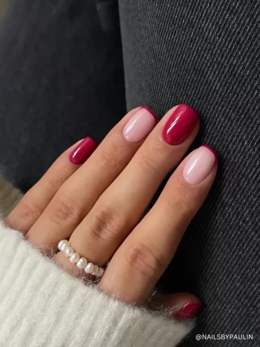 A chic manicure featuring a combination of deep red nails and soft pink nails with a red French tip design.