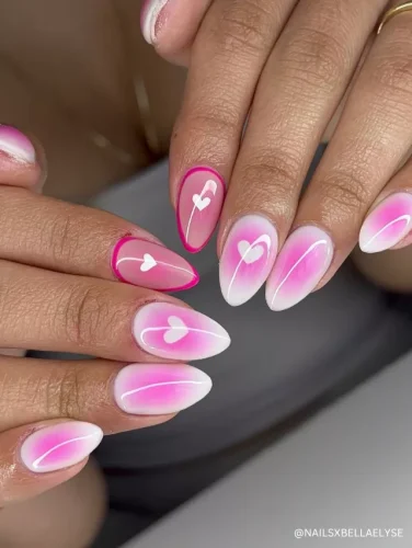 Romantic ombré pink and white almond-shaped nails featuring delicate heart accents and fine swirl details.