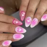 Romantic ombré pink and white almond-shaped nails featuring delicate heart accents and fine swirl details.