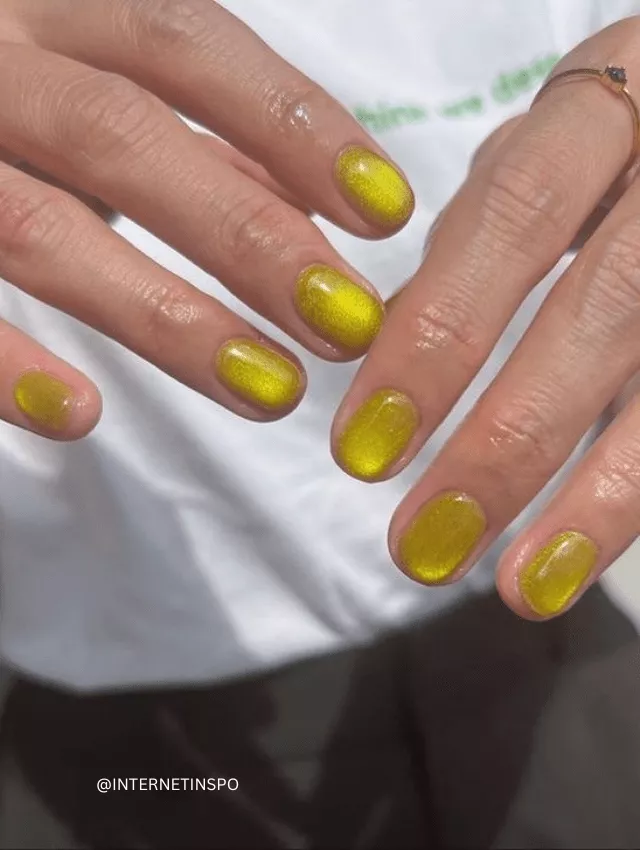 Short, rounded nails painted in metallic mustard yellow.