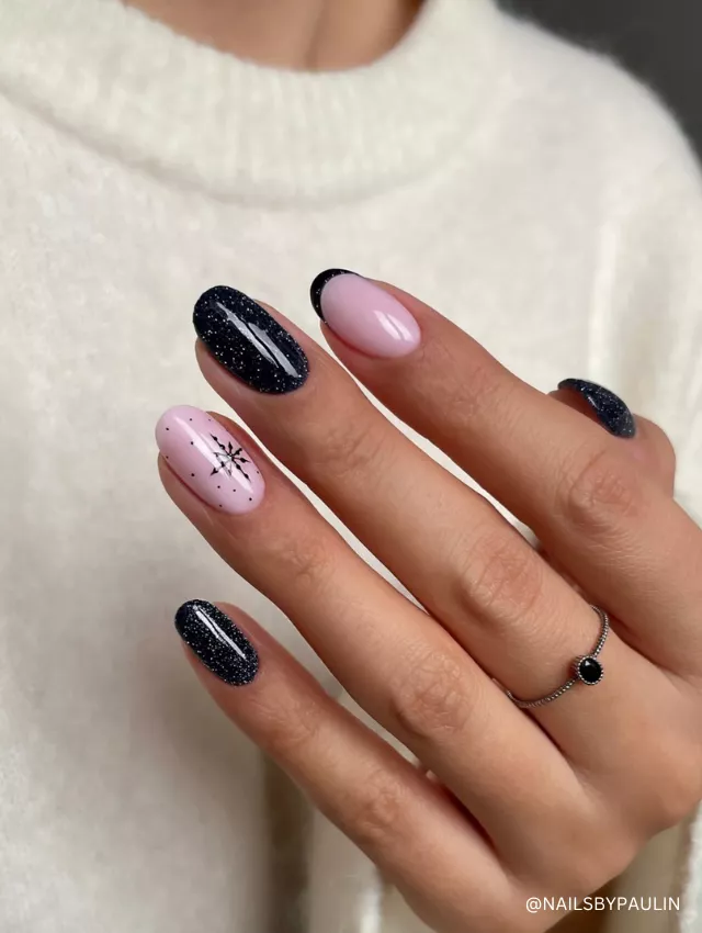 A celestial-inspired nail design featuring soft pink, black glitter, and a delicate star accent.