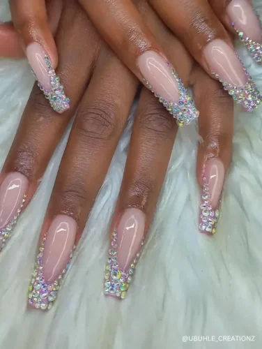 Elegant nude coffin nails adorned with dazzling rhinestone-encrusted French tips for a glamorous and luxurious finish.