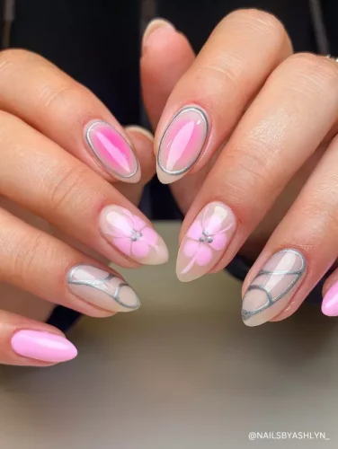 Chic pink and nude almond nails featuring silver-edged accents, floral 3D designs, and glossy finishes.