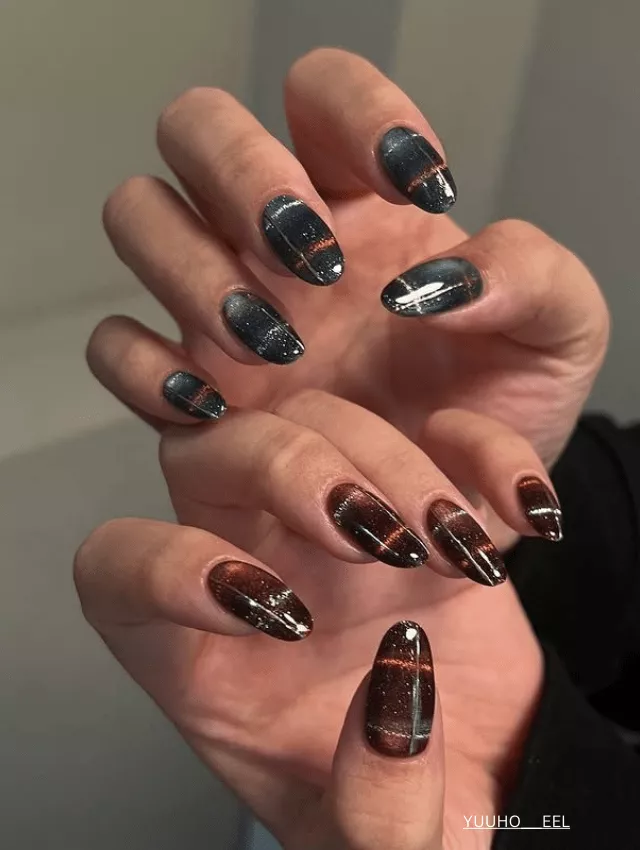 Cosmic-inspired velvet nails with black, brown, and gold streaks.