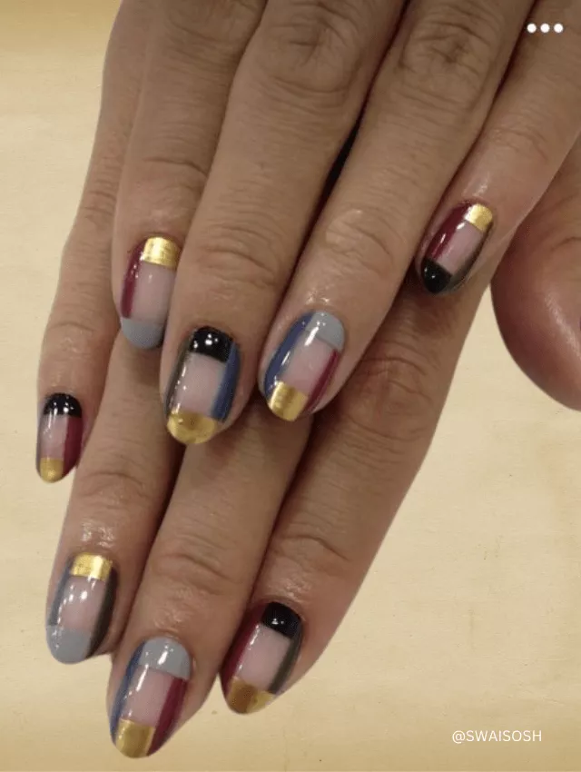 Short nails with geometric blocks of color and gold tips.