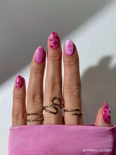 Sparkly pink nails with 3D heart embellishments and a glossy, eye-catching finish for a playful and bold look.