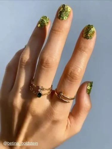 Chic nail art featuring green sequins on a nude base for a sparkling effect