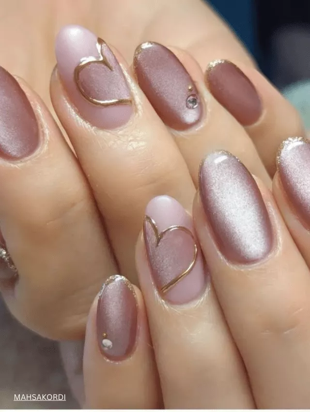 Nude velvet nails with gold heart embellishments and a subtle glow.