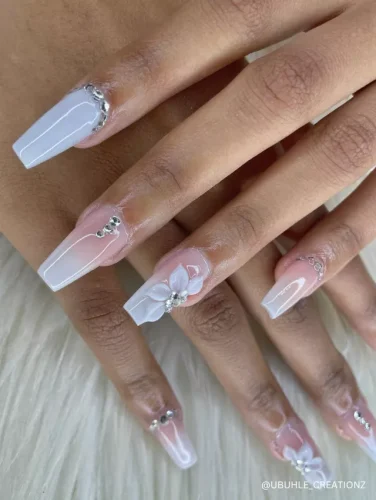 Elegant nude and white coffin nails featuring subtle rhinestone accents and delicate 3D floral designs for a timeless and sophisticated look.