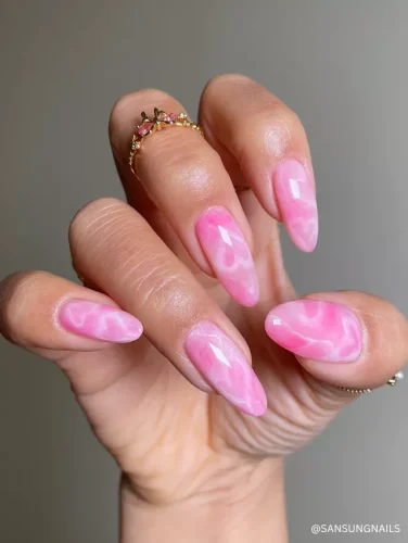 Elegant pink marble almond nails featuring a glossy finish and a fluid, dreamy swirl pattern.