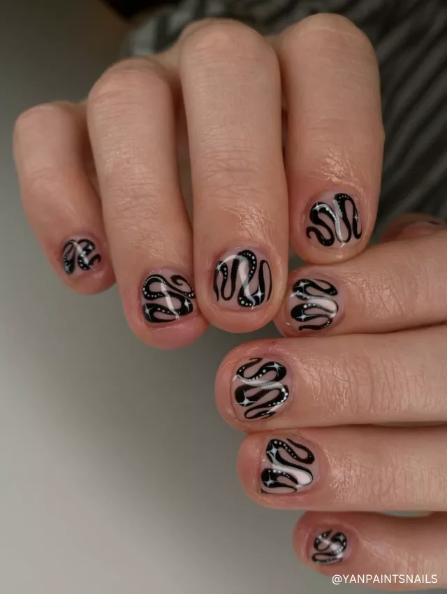 A playful black and white wavy swirl nail design on a nude base with intricate details.