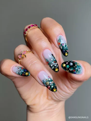 Enchanting almond-shaped nails with a smoky green ombré base, adorned with multicolored gemstones, pearls, and gold star accents for a magical, celestial look.