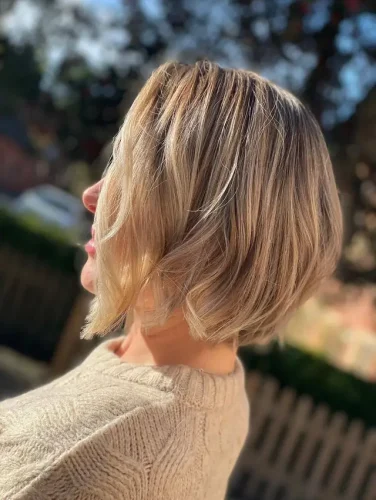 This hairstyle features a textured bob cut that beautifully blends shades of blonde and light brown, creating a vibrant, sun-kissed effect. The soft, subtle layers give the hair movement and volume, making it look effortlessly chic and modern. This 'Sunlit Textured Bob' is perfect for those seeking a low-maintenance yet stylish look that works well for both casual and formal occasions. The natural highlights enhance the dimensional texture, offering a fresh and youthful vibe. ✨🌞