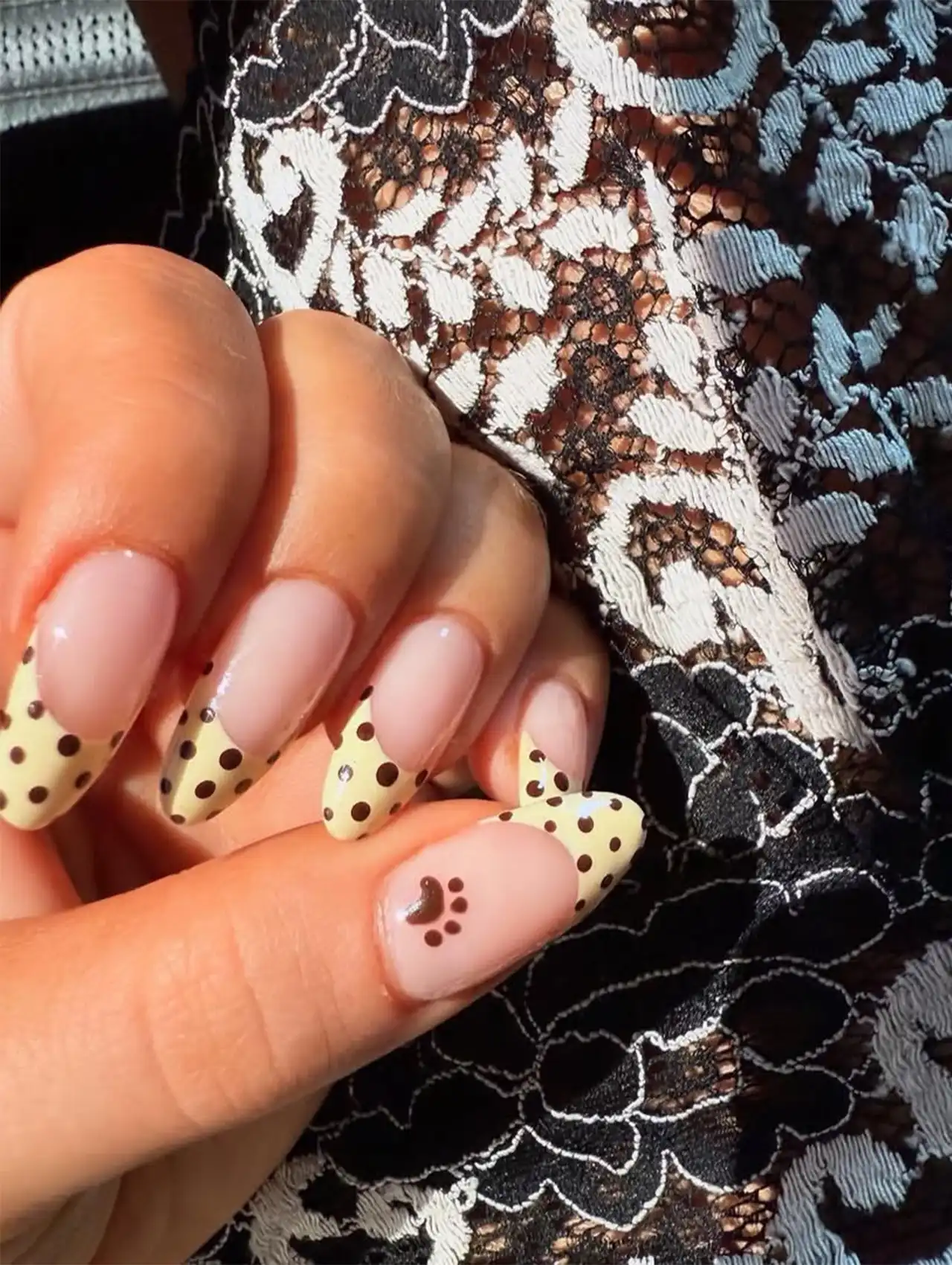 Sabrina Carpenter nails with beige and brown polka dots and a paw print accent