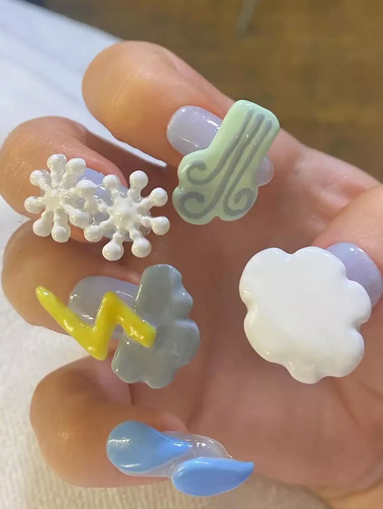 Sabrina Carpenter nails with 3D weather symbols like clouds, lightning, and snowflakes