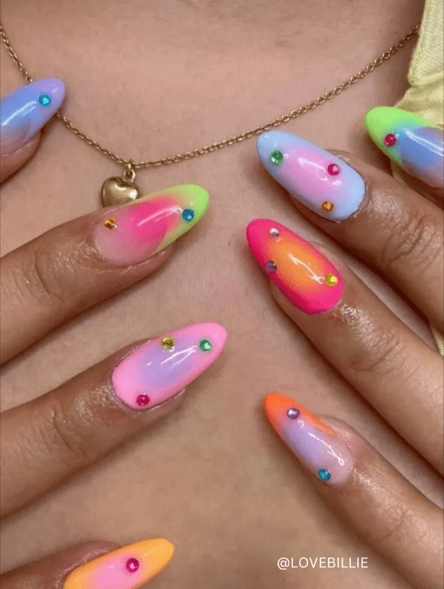 Vibrant neon ombre festival nails adorned with colorful rhinestones, perfect for festival fashion.