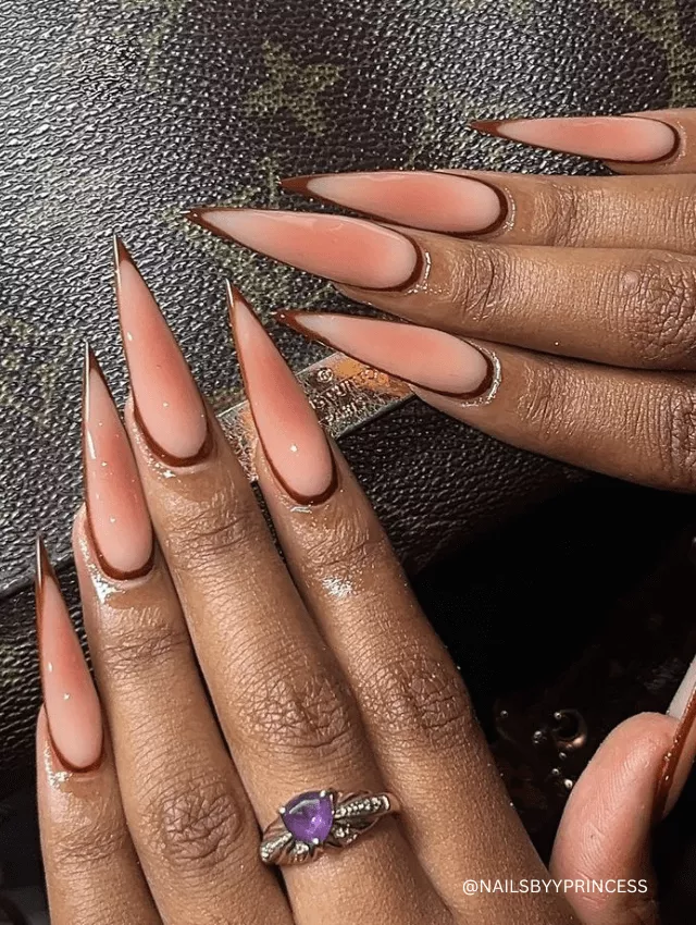 Long, sharp nude stiletto nails with brown French tips.