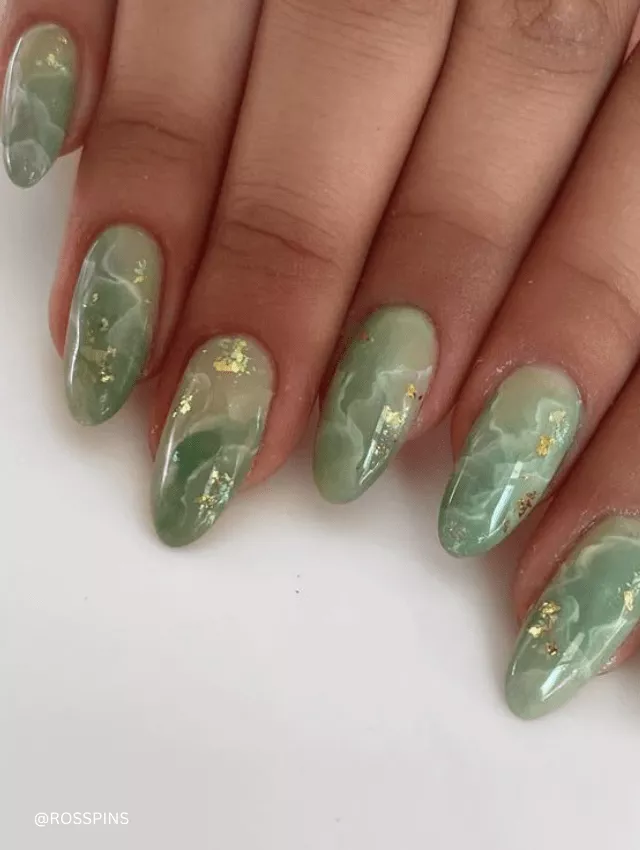 Green marble nails with white veining and gold flakes.