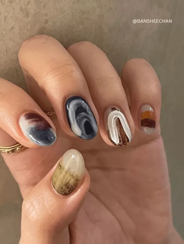 Mixed-color marble nails with abstract designs.