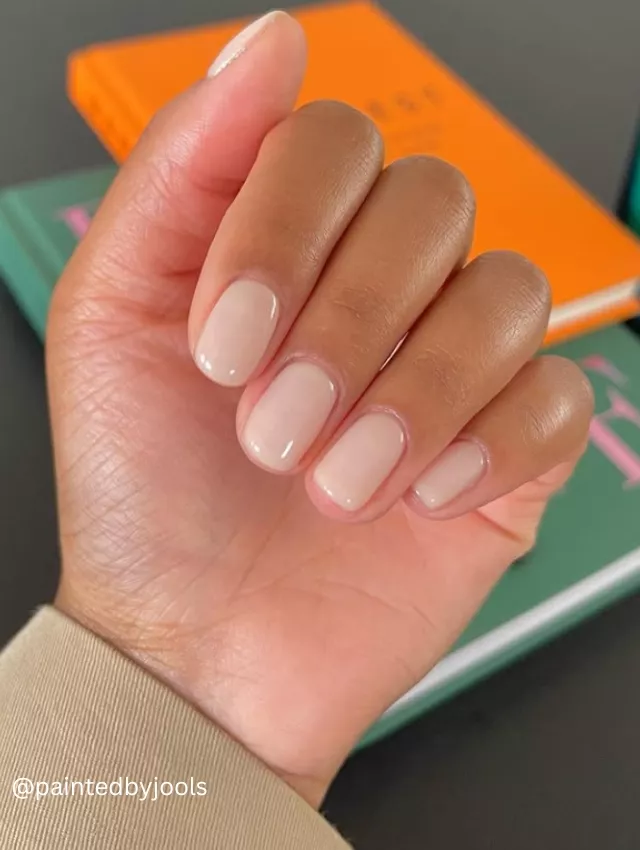 Close-up photo of a hand showcasing a classic French manicure with a glossy finish.