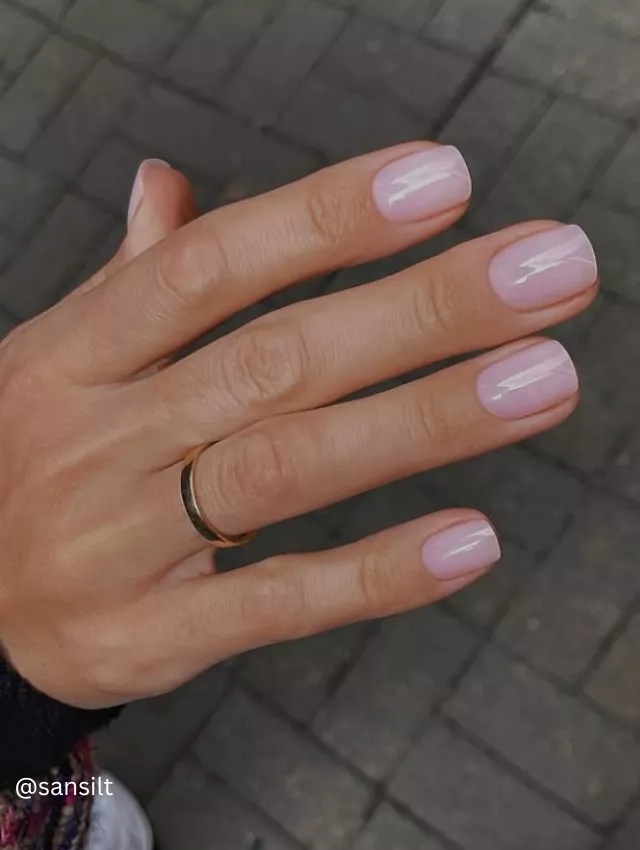 A hand flaunting an urban chic pink nail polish in an outdoor setting.