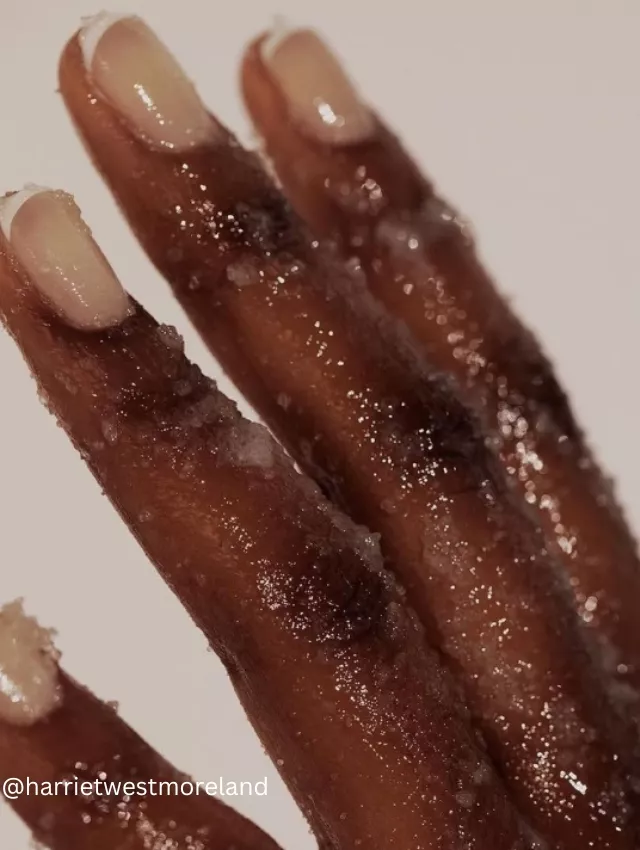 Close-up of hands covered in sparkling sugar-like particles showcasing a French manicure style, known as Soap Nails.