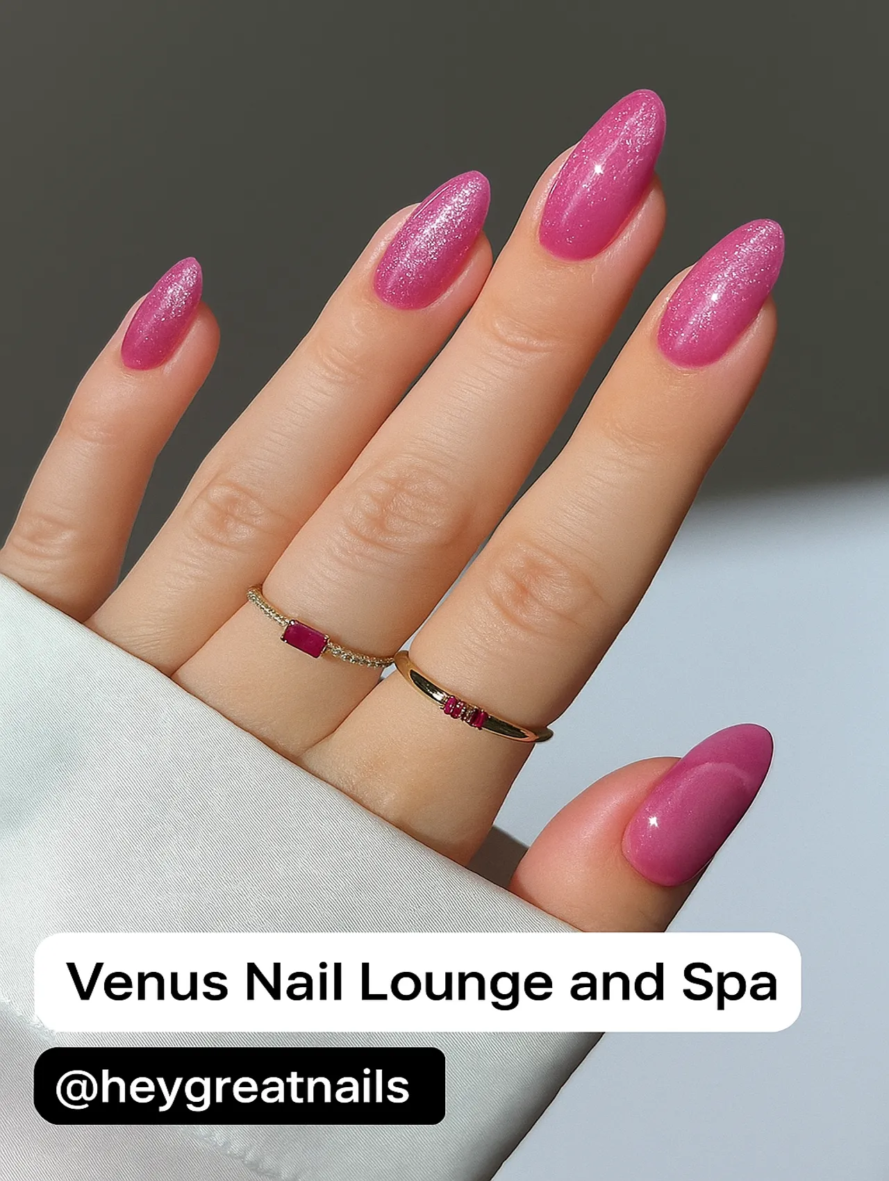 A close-up of elegant pink glitter nails from Venus Nail Lounge and Spa, featuring an almond shape and a smooth gradient shimmer.