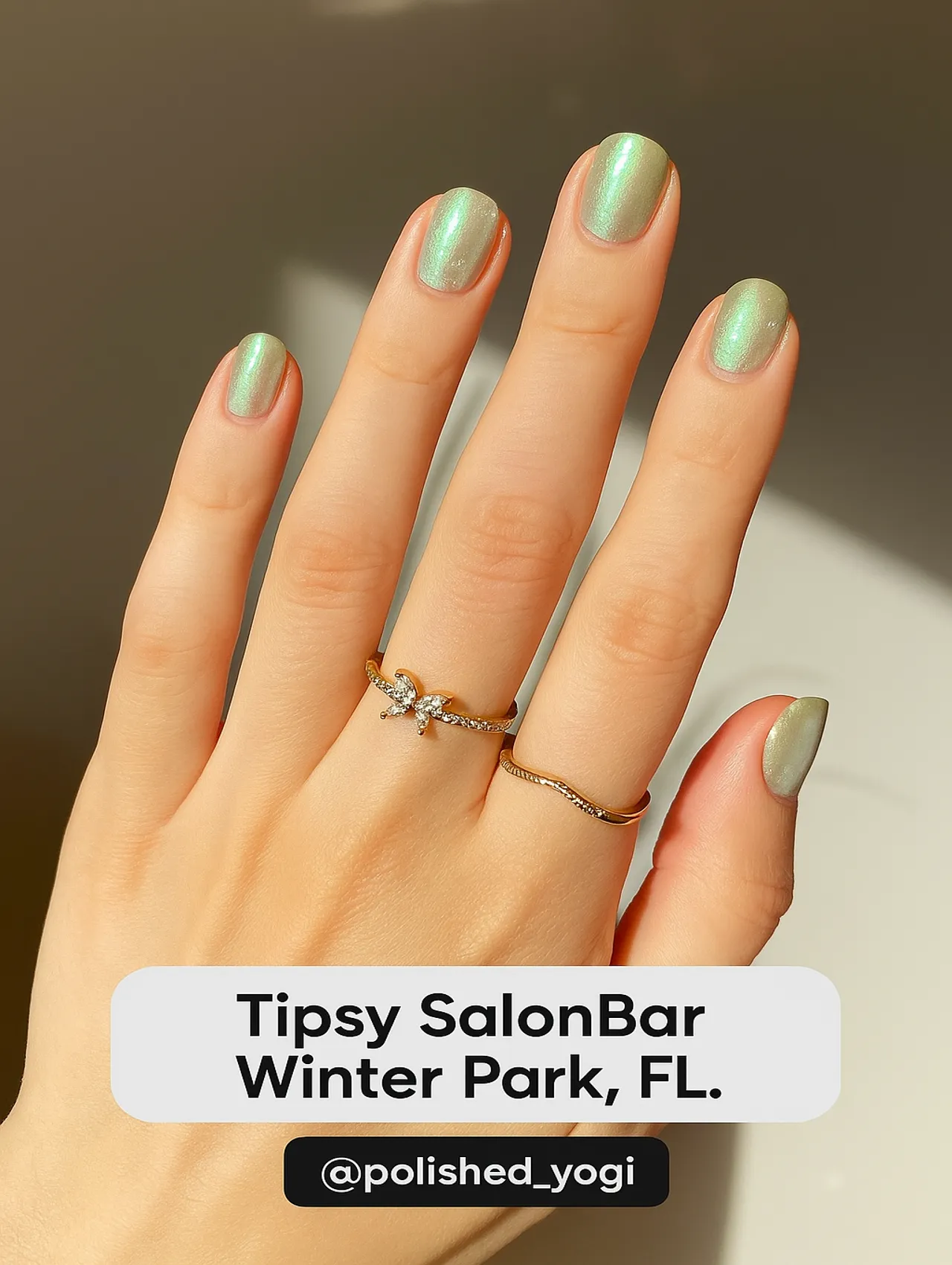 Close-up of short mint green shimmer nails from Tipsy SalonBar in Winter Park, FL, with a soft pearl finish and gold rings.