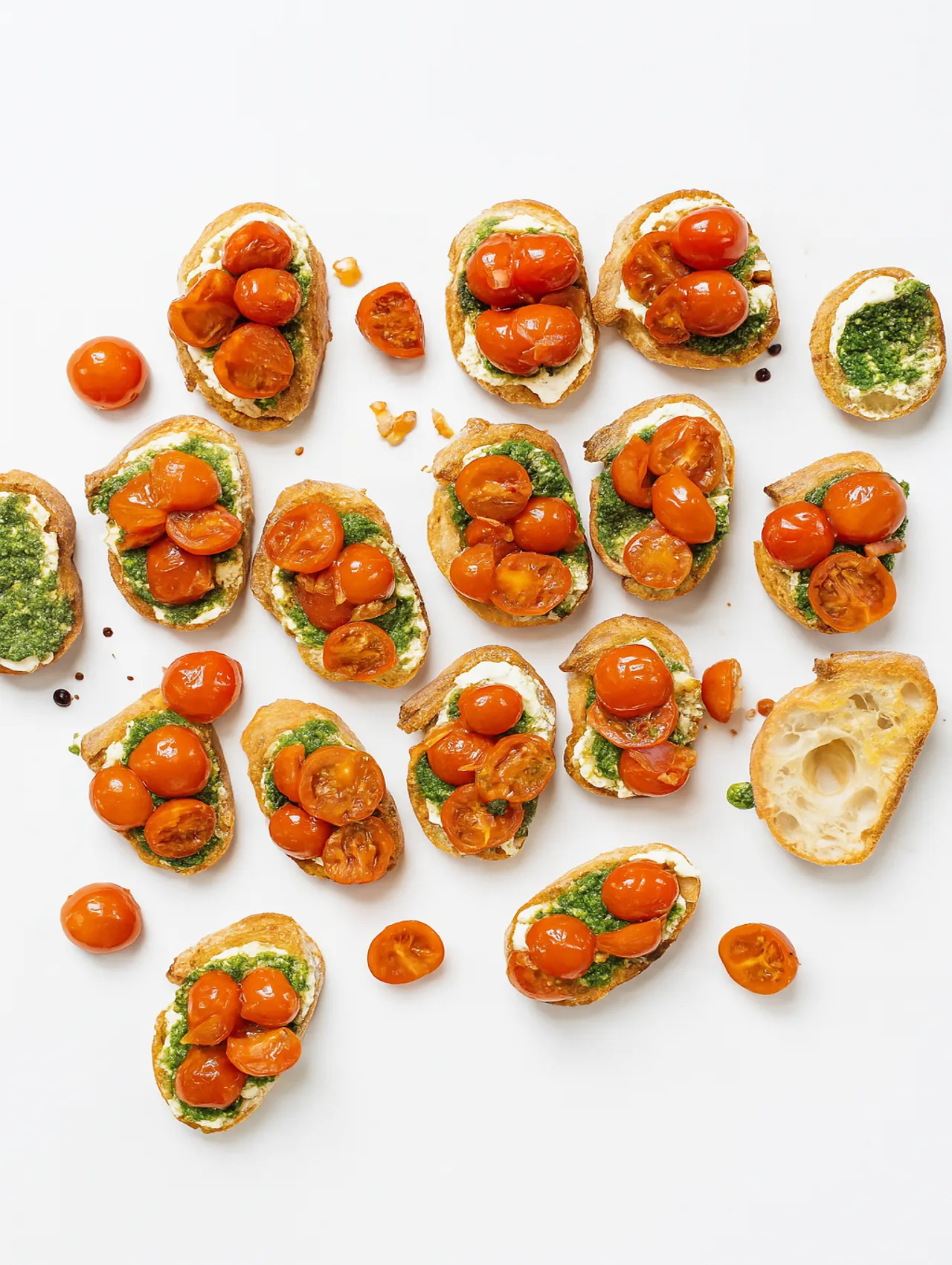 Bruschettas con pesto y tomate cherry servidas sobre pan crujiente en fondo blanco, ideales para eventos o reuniones