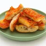 Trozos de pan crujiente untados con tomate fresco y ajo sobre un plato verde.