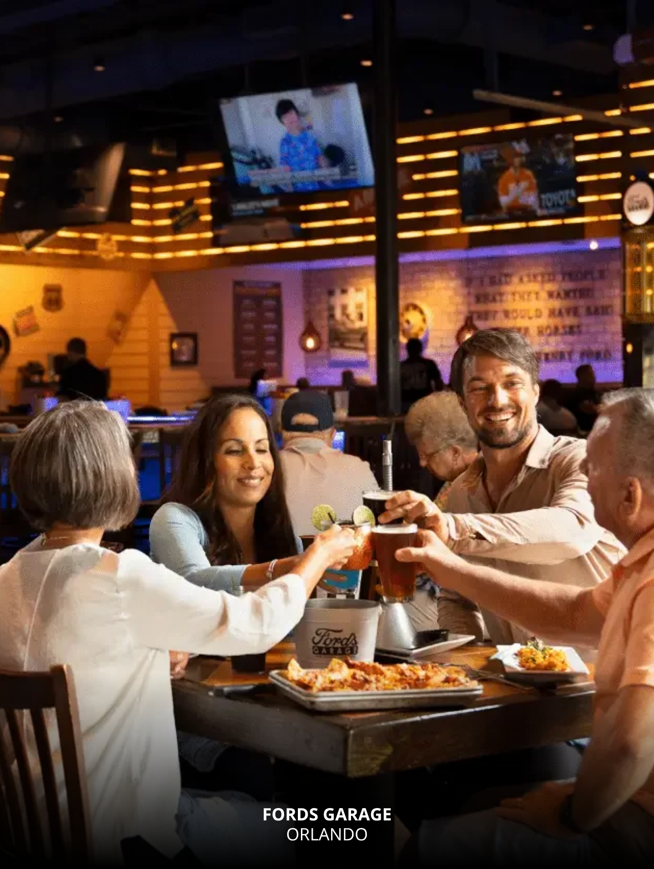 Group of friends toasting drinks with food at Fords Garage, Orlando Sports Bars