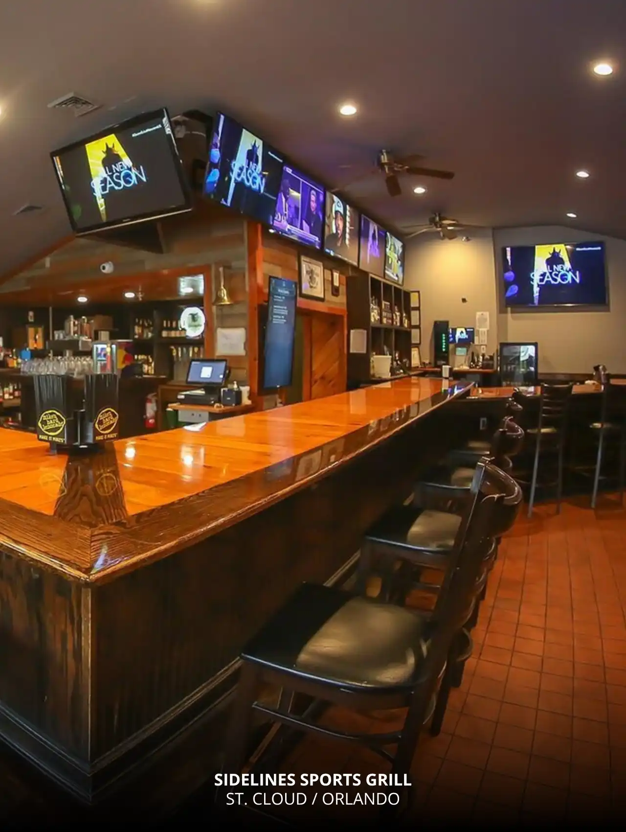 Wooden bar and multiple TV screens at Sidelines Sports Grill, one of the most welcoming sports bars in Orlando.