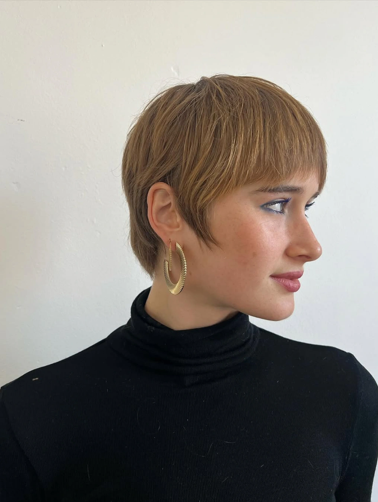 Woman with Classic Straight Pixie Cut Hairstyle in golden brown tone.