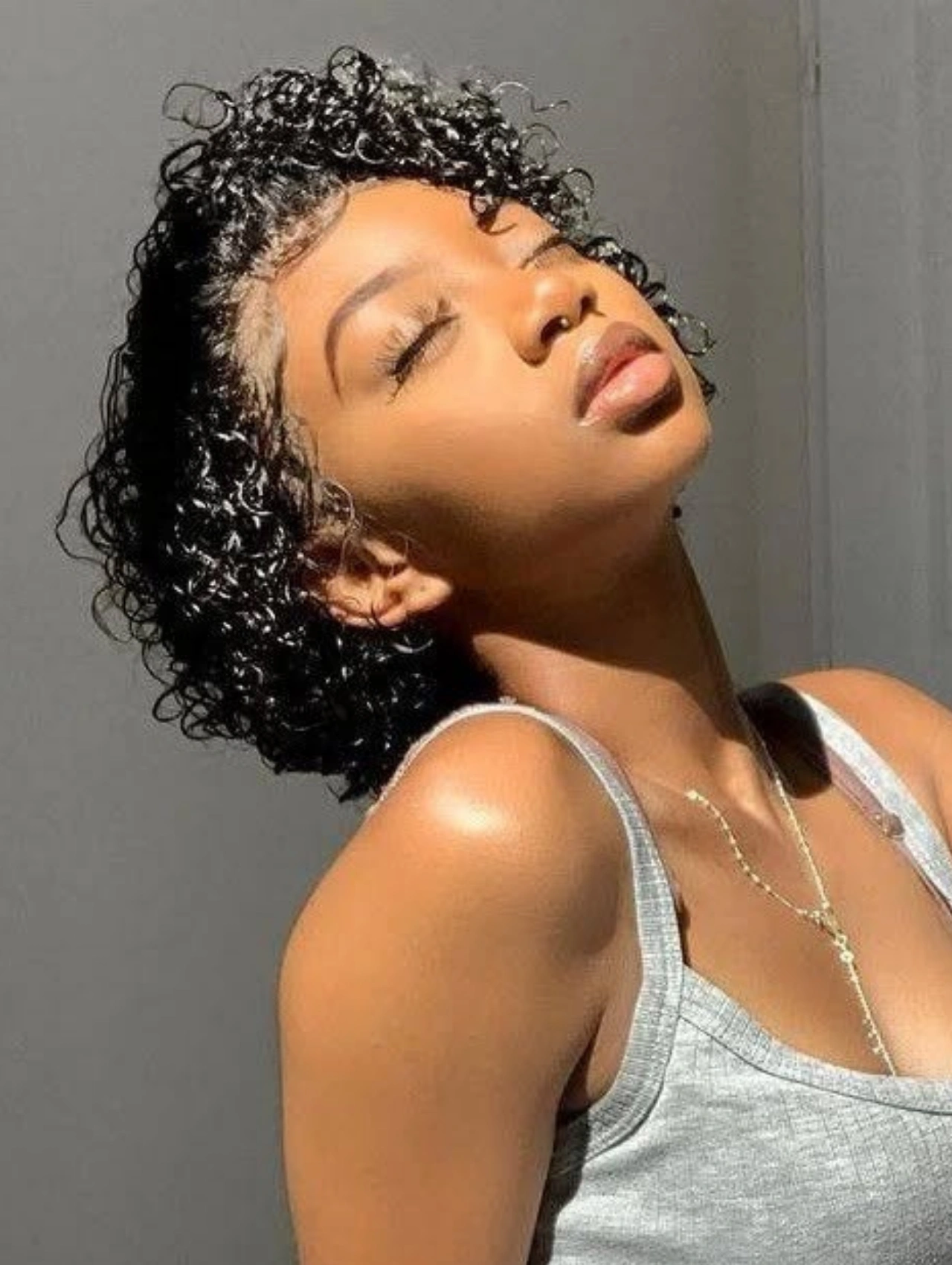 Woman with Curly Pixie Cut Hairstyle, natural short curls shining in sunlight.