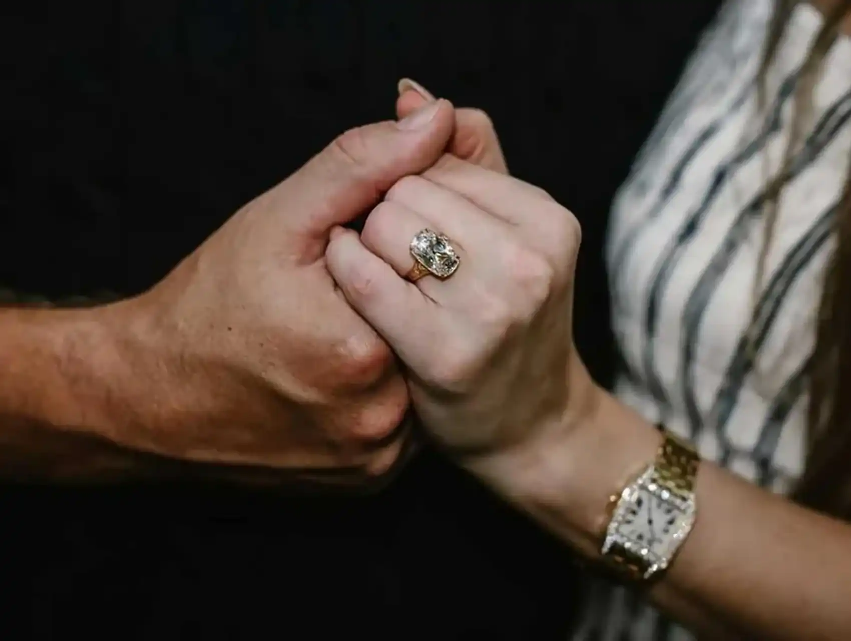 Close-up of Taylor Swift’s naked engagement nails and large diamond ring held hand-in-hand with her fiancé.