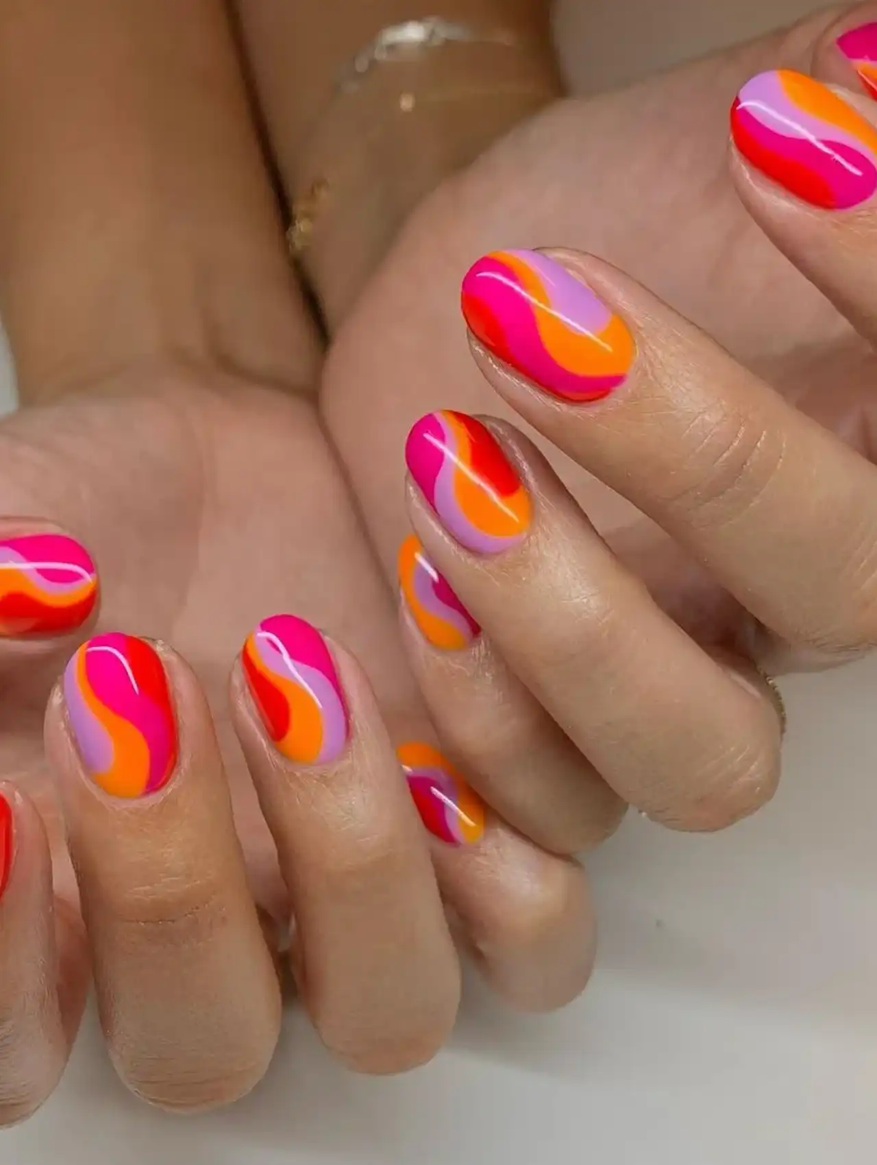 Uñas de Tendencia cortas con diseño abstracto en tonos naranja, rosa y lila