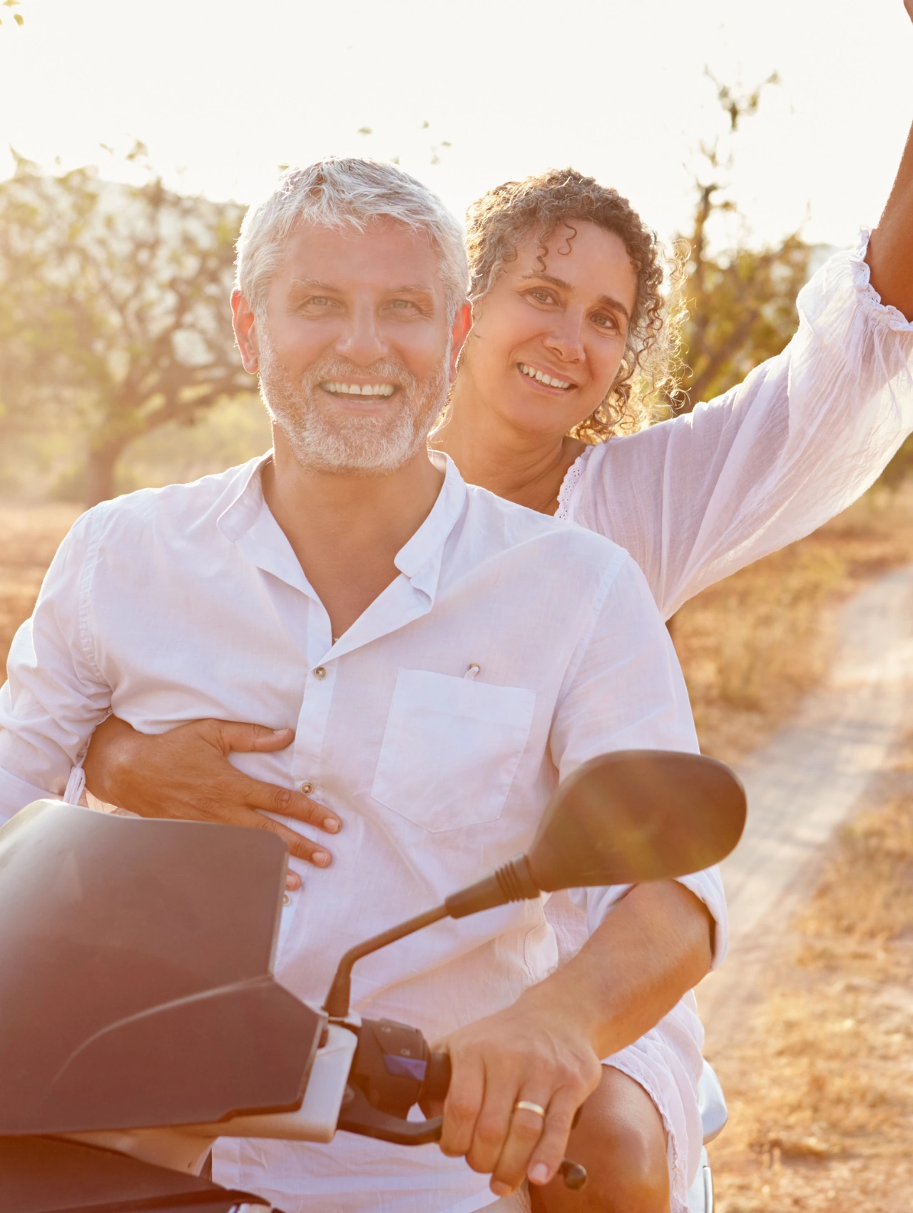 Pareja madura divirtiéndose en motocicleta, transmitiendo humor y frescura, ideal para mujeres divorciadas en busca de pareja.