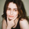 Young woman with visible skin bumps resting her chin on her hand, considering the best treatment for fungal acne